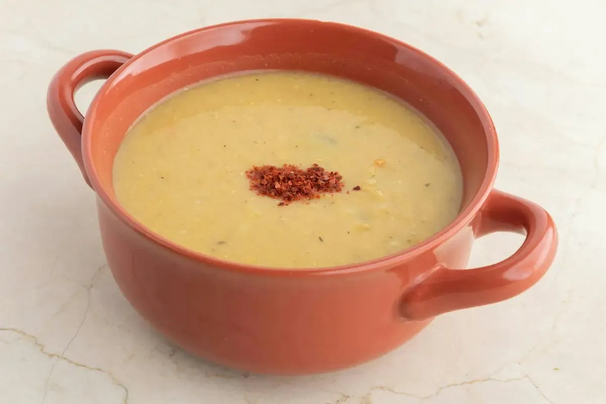 Caldo cremoso amarelo em panela de cerâmica